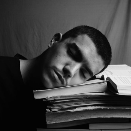 Estudante cansado sobre uma pilha de livros